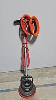 Full view of Oreck XL Pro Orbiter floor machine with upright handle and long red power cord wrapped around stand, showing attached base with branding and one brush attachment.