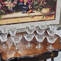 Group shot of various cut crystal stemware glasses with differing shapes and sizes on a wooden table