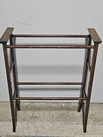 Front view showing the full wooden towel rack with three horizontal bars and angled legs.