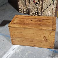 Closed wooden rectangular trunk with natural wood finish and visible wood grain.