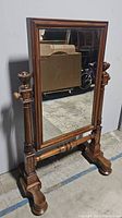 Front view of the large vintage wooden framed mirror showing the full mirror face supported by two detailed turned posts with carved finials and sturdy feet base.