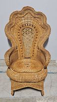 Front view of the large wicker rocking chair showing scalloped backrest and overall design.