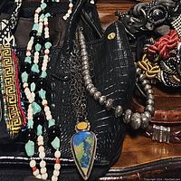 Three handbags with necklaces draped across