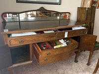 Wide front view of wooden buffet with mirrored back, drawers pulled out showing contents and drawer craftsmanship.