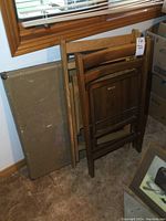 Folding card table leaning against the wall, showing wear and vintage condition.