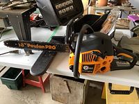 Side view of assembled chainsaw on table, showing 18" bar and orange/black housing