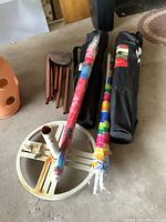 Overview of two beach umbrellas sealed and two black carrying bags for foldable chairs, patio umbrella stand base, and wooden wind chime tubes.