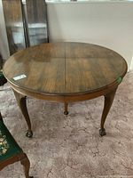 Full view of round wooden dining table showing split center for leaves and wood grain finish