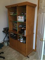 Front-left angle view of wooden two-piece display cabinet showing open shelves and sliding doors at the bottom, with various items on shelves (not included).