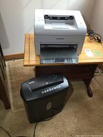 Samsung ML-2510 laser printer and Staples shredder side by side on a wooden table and carpeted floor
