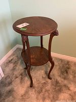 Full view of two tiered round wooden table showing overall design and claw feet stature.