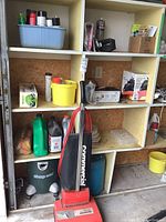 Wide shot of shelving with MotoMaster charger, Shop-Vac vacuum, oils, yellow bucket, and other supplies.