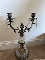Full view of the antique two-arm candelabra showing the overall shape, arms, and candle holders with hanging crystal prisms.