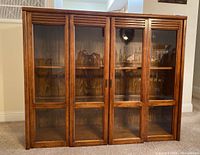 Front view of display case showing four glass doors and wood frame with horizontal slats on top.