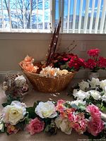 Full view of the lot showing basket with dried flowers, ceramic vase with dried pink flowers, glass container with decorative balls, and wreaths on floor.