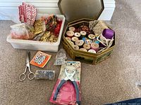 Wide view of all sewing supplies including threads, ribbon, beads, scissors, pincushion, and eyelet tool