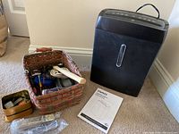 Overall view of the Staples shredder next to basket of miscellaneous tools and manual in front