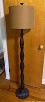 Full view of tall floor lamp with dark brown plastic stem and tan fabric shade, showing its height and overall condition.