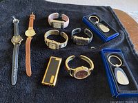 Full lot showing seven vintage wristwatches of various brands and styles, two boxed silver-tone keychains, and two gold-tone vintage lighters.