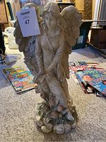 Full view of 18 inch tall beige resin angel statue holding flowers and birds with detailed wings