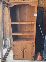 Front view of wood display cabinet showing three shelves, two drawers, and lower cabinet with carved doors.