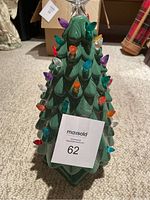 Front view of ceramic Christmas tree with multicolored light bulbs attached and star on top.