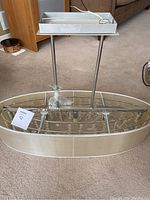 Full view of pendant chandelier showing oval beige fabric shade with silver metal frame on carpeted floor.