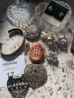 Photo of the costume jewelry including brooches, copper cuff bracelet, rhinestone earrings, and tartan accessories on a marble surface.