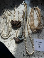 Lot of five assorted faux pearl necklaces with pendants and chain accents.
