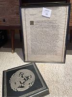 Framed Desiderata poem poster and decorative wood box with dragon design on lid placed on stone surface.