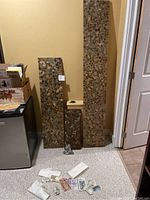 Three vertical wooden coin boards of varying heights densely covered with foreign coins, with some coins falling off. Several assorted foreign paper bills laid on the carpet in front.