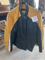 Front view of the jacket showing front zipper, black leather body, yellow shoulders, and white stripe on the sleeve