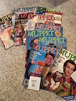 Photo showing full set of 13 Muppet Magazine issues fanned out on carpet with readable titles and colorful covers