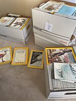 Four bankers boxes filled with National Geographic magazines, some vintage and some complete sets from early 1990s to 2017. Visible magazines show distinctive yellow borders.