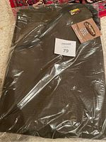 Snake gaiters in original plastic packaging showing dark fabric and Rattlers Brand logo patch with tags attached.