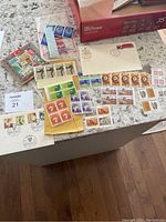 Image showing various stamps laid out on a table including Canadian and Turkish stamps, first day covers, and loose stamps in sheets or strips.