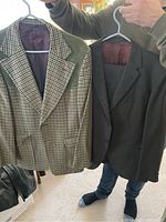 Front view of two vintage men's suit jackets - checked pattern jacket with green suede patches and a solid dark jacket.