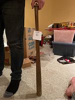 Full view of vintage wooden baseball bat held upright by person, showing length and shape