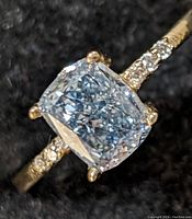 Top-down close-up of cushion-cut center diamond and pavé accent diamonds on band.