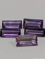 Five rectangular-cut genuine amethyst gemstones with purple coloration and good clarity.