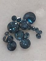 Close-up of assorted loose round faceted blue diamonds on white background