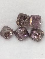 Close-up photo of five deep pink rough diamonds arranged together on white background, showing natural shapes and inclusions.