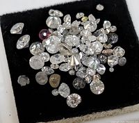 Top-down view of loose diamond stones on black velvet insert
