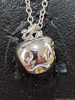 Close-up image showing the sterling silver rhodium plated pendant shaped like a pomegranate with gold-toned interior details and small diamond accent.