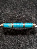 Close-up photo of sterling silver turquoise ring showing three rectangular blue turquoise stones with matrix and silver end caps against a black background.