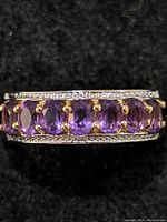 Close-up photo of the sterling silver ring with seven oval amethyst stones showing the front and side details on a black background.