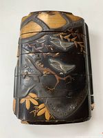Front view of antique Japanese Inro showing silver cranes and gold bamboo decoration with visible cracks and wear.