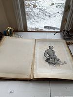 Photo showing open book with visible binding damage and a portrait etching of a uniformed military officer holding a hat, with foxing on the page.