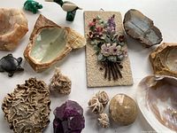 Overview of assorted natural items including carved turtles and birds, seashells, rock slices, desert rose minerals, and floral stone plaque