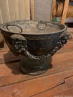 Front angle showing footed base, pedestal, decorative mask head and garland swags